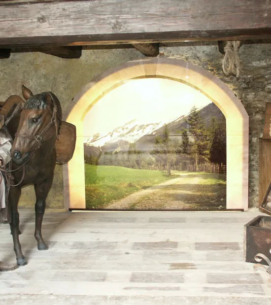 Medieval traveler with horse in rustic stone stable featuring scenic mountain backdrop